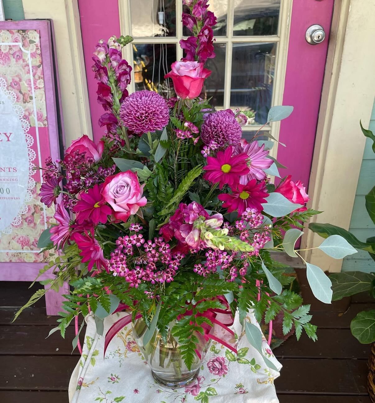 Vibrant hot pink arrangement of roses, snapdragons and mums